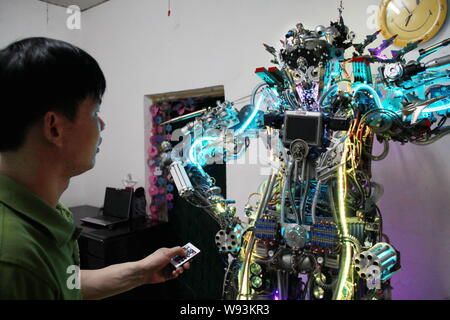 Chinese farmer Tao Xiangli uses a remote control to operate his robot made from scrap at home in Beijing, China, 16 May 2013.   Tao Xiangli, a 37-year Stock Photo