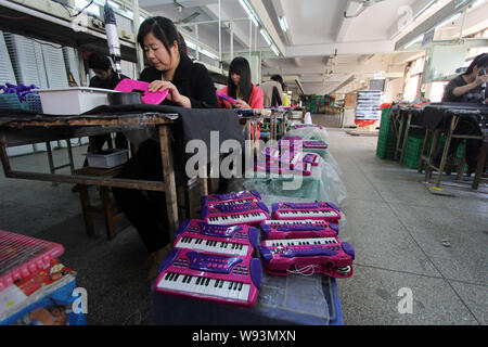 --FILE--Chinese workers manufacture electric toy pianos at a toy factory in Jinjiang city, southeast Chinas Fujian province, 24 March 2012.   Toy expo Stock Photo