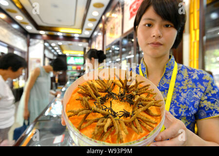 --FILE--A Chinese clerk shows parasitic fungus, Cordyceps sinensis, from Tibet at a store in Yiwu city, east Chinas Zhejiang province, 30 July 2013. Stock Photo