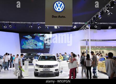 --FILE--Visitors look at a Tiguan SUV and other cars at the stand of Shanghai Volkswagen, a joint venture between SAIC and VW, during an automobile ex Stock Photo