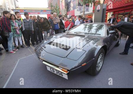 Tourists look at an old timer car of Maserati during the Classic Cars  Challenge China 2013 on the Wangfujing shopping street in Beijing