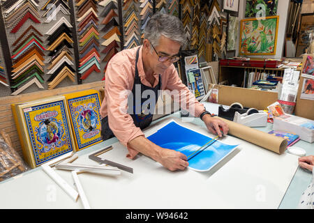 frame maker man measures picture for framing in a framing shop Stock Photo