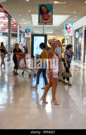 Lady looking at the shops in a busy shopping mall in France Stock Photo