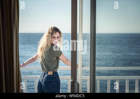 Blond woman lsmilling at the camera from hotel room Stock Photo