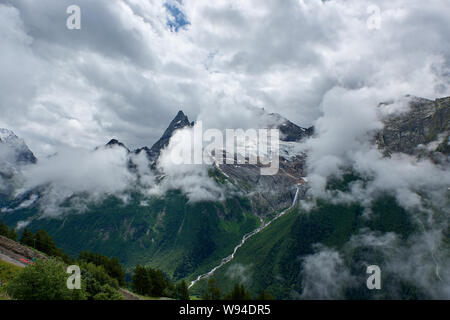 Mountain green ridge covered by pine trees in the fog and clouds. Dombay, Russia Stock Photo