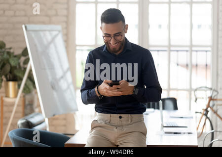 Smiling young business man using phone in modern creative office Stock Photo