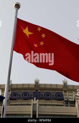 --FILE--A Chinese national flag flutters in front of the headquarters building of COSCO in Beijing, China, 30 March 2013.   Shipping giant China Cosco Stock Photo
