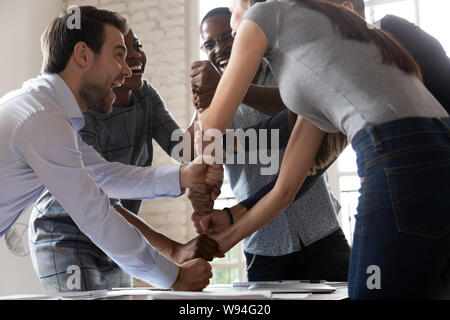 Overjoyed multiracial business team stacking fists motivated by corporate success Stock Photo