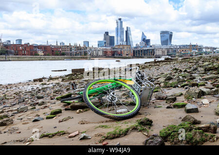 A Limebike hire bicycle, dumped in the River Thames and washed up on the shore at low tide, Blackfriars, London, UK Stock Photo