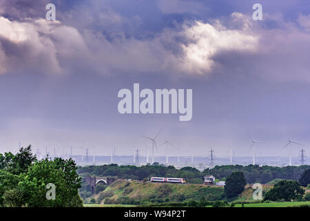 A Transport for Wales Class 175 diesel train passing Frodsham signalbox. Frodsham marshes windfarm in the background. Stock Photo