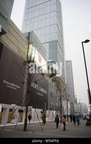 Pedestrians walk under a giant panda-shaped art installation being installed on the facade of the Chengdu IFS shopping mall in Chengdu city, southwest Stock Photo