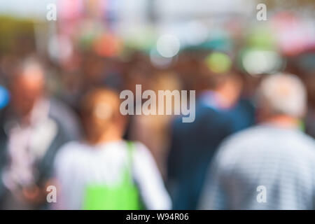 Crowd of anonymous men and women walking down an urban sidewalk with ...