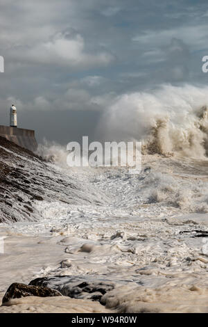 Huge breaking waves next to a lighthouse on a stormy day (Porthcawl, Wales, UK)