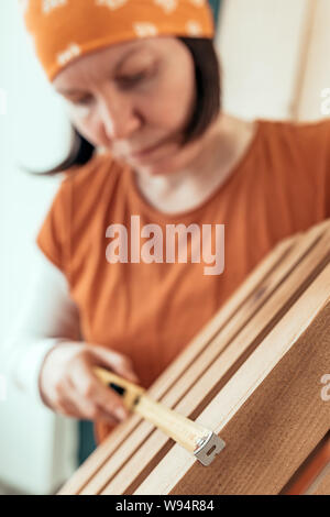 Female carpenter tape measuring wooden crate in her small business woodwork workshop Stock Photo