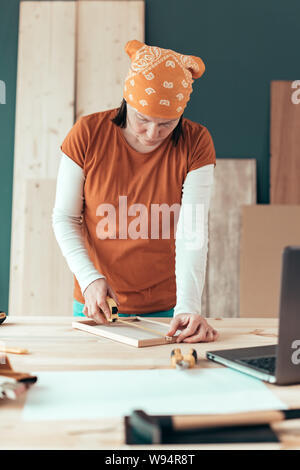 Female carpenter tape measuring picture frame in small business woodwork workshop Stock Photo