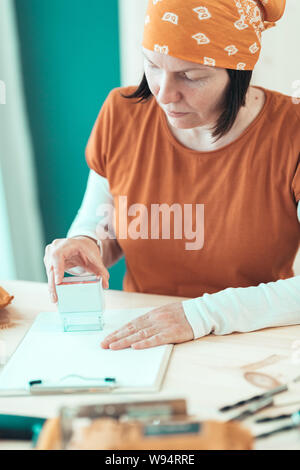 Self employed female carpenter is stamping project documentation in small business woodwork workshop Stock Photo