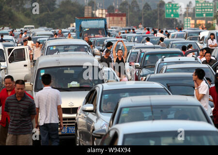 Chinese holidaymakers rest next to their cars as they are waiting in a long queue in a traffic jam on an expressway during the Mid-Autumn Festival and