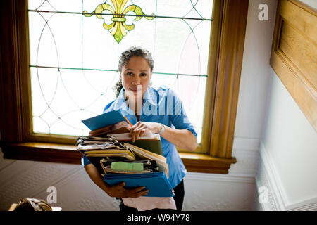 Woman holding stack of files on staircase Stock Photo