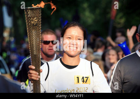 Chinese tennis player Li Na holding the Olympic torch jogs during the Torch Relay of the London 2012 Olympic Games in Haringey, London, UK, 25 July 20 Stock Photo