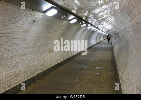 Interior of Greenwich foot tunnel that connects both sides of London under river Thames, lit by neon lights, wide angle photo with blurred pedestrians Stock Photo