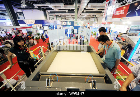 Visitors look at a model floataion tank for water purifying during the Fifth Shanghai International Water Exhibition, also known as Aquatech China 201 Stock Photo