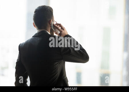Rear view confident businessman talking on phone with business partner Stock Photo