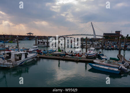 Crepuscular rays, sunlight streams through small holes in the clouds, Lover's Bridge, small fishing boats, Tamsui Fisherman's Wharf, Taipei, Taiwan Stock Photo