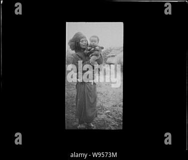 Ainu woman holding a child standing outside Stock Photo