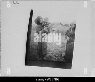 Ainu woman standing outside holding a child Stock Photo