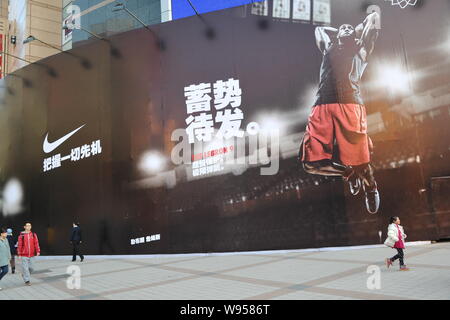 Pedestrians walk past a giant Nike outdoor advertisement in