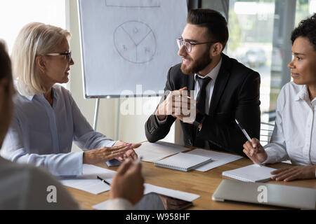 Diverse business partners discussing project, mature leader holding briefing Stock Photo