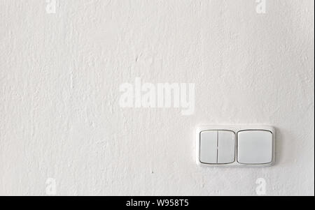 Old light switches on white wall freshly painted, some drops of paint over plastic Stock Photo