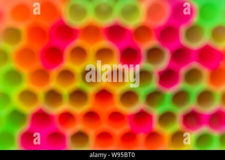 Blurred background of multicolored  plastic cocktail tubes. Backgdrop of bright yellow, red, pink and green neon colors. Abstract colorful background. Stock Photo