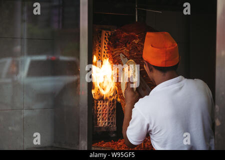 man in front of kebab spits - fire in background Stock Photo