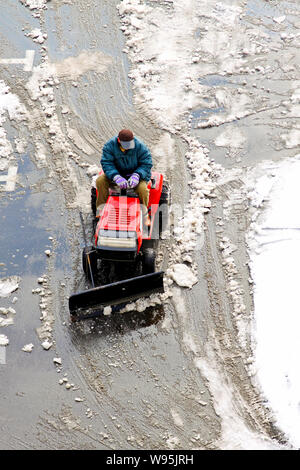 Man operating machine removing snow from street Stock Photo