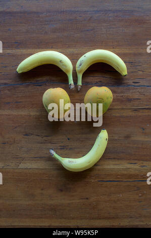 A smiling face made out of different fruits on a wooden table Stock Photo