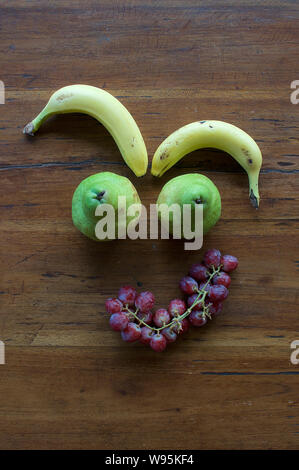 A funny face made out of different fruits on a wooden table Stock Photo
