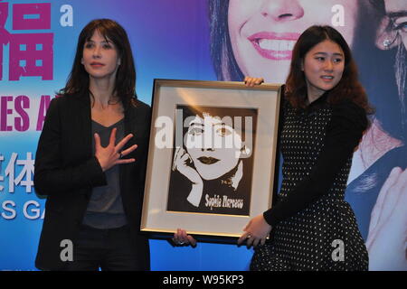 French actress Sophie Marceau, left, is presented a painting during  a press conference for the movie, Happiness Never Comes Alone, in Beijing, China, Stock Photo