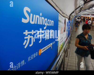 --FILE--Pedestrians walk past advertisements for online shopping site Suning.com in Beijing, China, 15 July 2012.   To enhance its capital capacity an Stock Photo