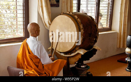 Buddhist monk drumming in small temple at Shanti Stupa (World Peace Pagoda) on Anadu Hill, Pokhara, Nepal Stock Photo