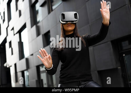 Female Using Virtual Reality Glasses And Wearing Black In Futuristic City Stock Photo