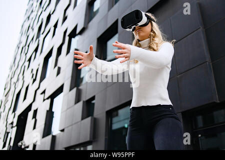 Woman Wearing VR Glasses In Front Of Urban Looking City Building Stock Photo