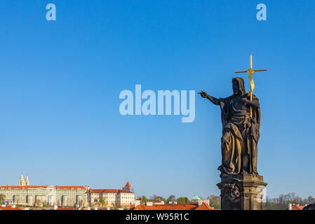 view of Statue of Saint  John the Baptist stand on pedestal and balustrades of Charles Bridge over Vltava river and background of Praha Castle.