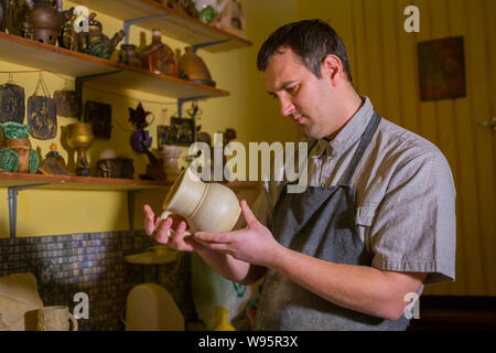 Professional male potter examining jug in pottery workshop Stock Photo