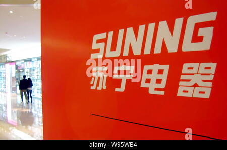 --FILE--Pedestrians walk past an advertisement for home appliances retailer Suning in Shanghai, China, 11 April 2012.   To enhance its capital capacit Stock Photo