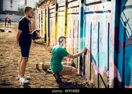 Kharkiv, UKRAINE July 30, 2019: A fellow draws bright street graffiti on an opening of youth park day. Stock Photo