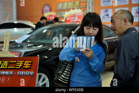 --File--Customers look at a leaflet of second-hand car at an exhibition in Guiyang, southwest Chinas Guizhou province, 12 April 2012.   The Chinese ri Stock Photo