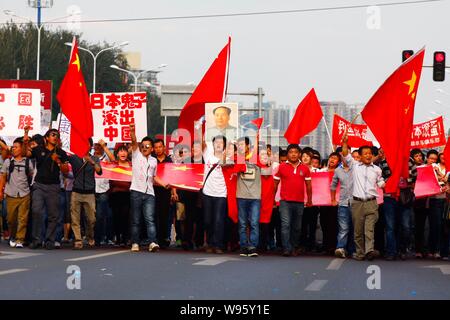 Chinese protestors wave Chinese national flags, hold up banners and shout slogans during an anti-Japan protest parade in Beijing, China, 15 September Stock Photo