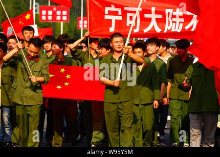 Chinese protestors dressed in the Red Army costumes wave Chinese national flags and hold up banners during an anti-Japan protest outside the Embassy o Stock Photo
