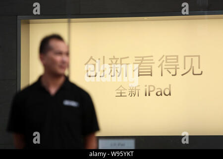 A Chinese staff member stands in front of an advertisement for the New iPad tablet PC at the Apple Store on the Nanjing Road shopping street in Shangh Stock Photo